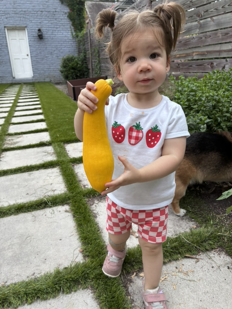 Lucy holding her squash in the backyard